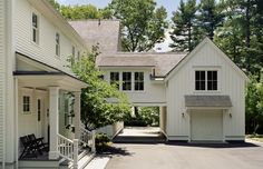 the house is white and has two garages on each side, with one door open