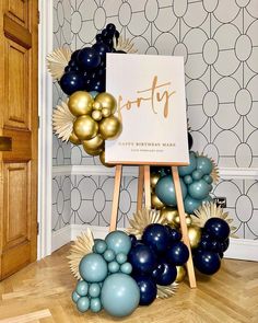 a birthday sign surrounded by balloons and gold foil stars on a wooden easel in front of a wallpapered background