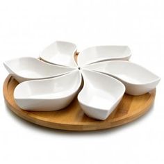 four white bowls are arranged on a wooden platter