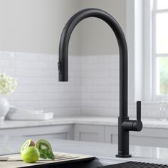 a black faucet in a white kitchen with green apples on the counter top