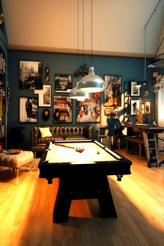 A stylish game room featuring a pool table in the foreground, vintage posters on a dark blue wall, and a hanging industrial light illuminating the space. Small Billiard Room, Room Ideas Hippie, Room Inspiration Vintage, Vintage Playroom, Pool Rooms, Billiard Room