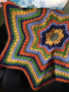 a colorful crocheted blanket is being held up