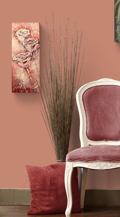 a white chair sitting next to a pink wall and a vase filled with flowers on top of a hard wood floor