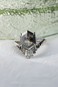 a diamond ring sitting on top of a white cloth covered table next to a glass bowl