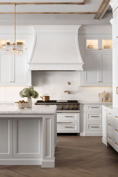 a kitchen with white cabinets and an island in the middle, surrounded by wood flooring