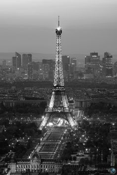 the eiffel tower lit up at night in black and white with city lights