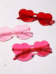 three heart shaped glasses are sitting on a white surface with pink and red hearts attached to them