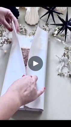 someone is wrapping something in white paper on a table with star decorations and other items