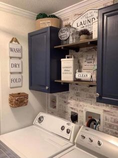 a washer and dryer in a laundry room with blue cabinets, hanging signs on the wall