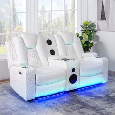 two white leather reclining chairs with speakers on the back and armrests, in front of a window