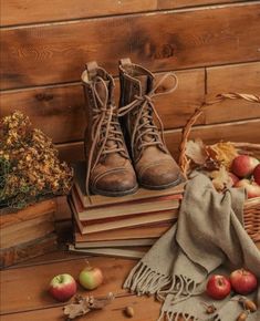 an old pair of boots sitting on top of books next to apples and other fruit