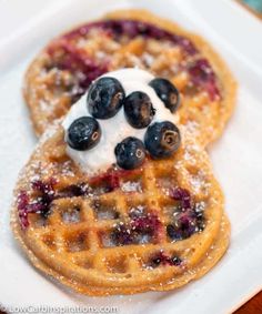 two waffles with blueberries and whipped cream on top are sitting on a white plate