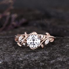 a close up view of a diamond ring on top of a rock with leaves around it