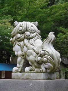 a stone lion statue in front of some trees