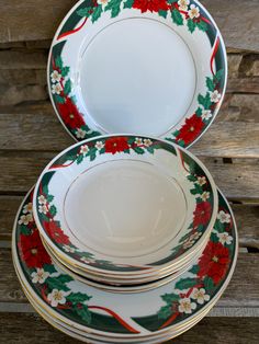 three plates with holly and red flowers on them sitting next to each other in front of a wooden wall