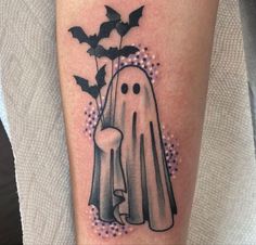 a black and white tattoo with a ghost holding a spooky bat next to a flower