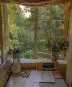 an open window in a room filled with lots of plants and art supplies on top of a table