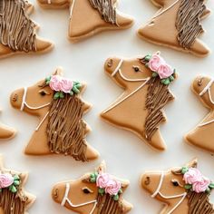 decorated cookies in the shape of horses with pink flowers on their heads are arranged neatly