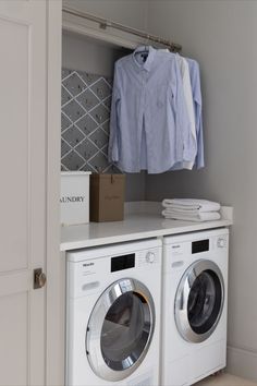 a washer and dryer in a room with clothes hanging on the rack next to each other