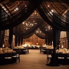 an indoor wedding venue with black drapes and white flowers on the tablecloths