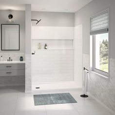 a white bathroom with two sinks and a walk in shower next to a large window