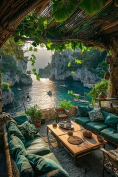 an outdoor living area with green couches, tables and chairs on the ground next to water