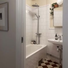 a bathroom with a checkered floor and white tile on the walls, along with a bathtub