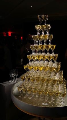 a very tall stack of wine glasses sitting on top of a table in a room