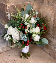 a bouquet of white flowers and greenery on a stone floor next to a wall