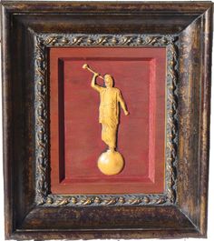 a painting with a gold statue on it's side and a red frame around it