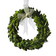 a green wreath with white ribbon hanging on a wall