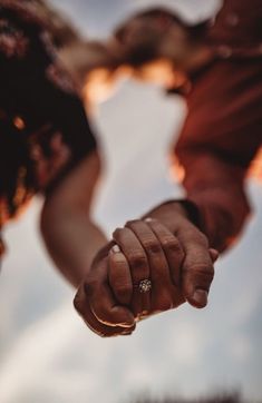 two people holding hands with the sky in the background