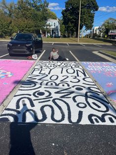 a person kneeling down on the side of a road next to some chalk drawings and trees