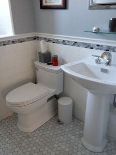 a white toilet sitting next to a sink in a bathroom on top of a tiled floor