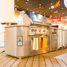 an outdoor kitchen with stainless steel appliances and wood flooring