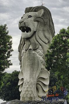 a large stone lion statue in front of some trees