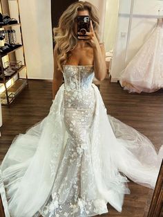 a woman taking a selfie in front of a mirror wearing a white wedding dress