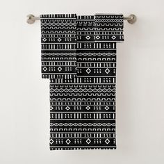 a black and white towel hanging on a metal hook in front of a white wall