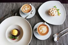 two plates with desserts on them sitting on a table next to utensils