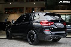 a black bmw suv parked in front of a building