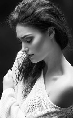 black and white photograph of a woman with her hair blowing in the wind, wearing a sweater