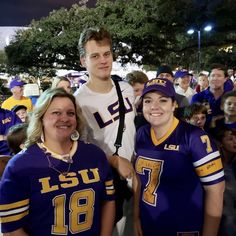 two women and a man are posing for a photo in front of a large group of people