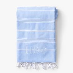 the monogrammed towel is blue with white stripes and letters on it, along with two tassels