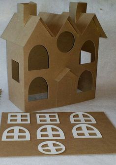 a cardboard house with cut out windows next to it