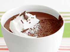 a white bowl filled with chocolate and whipped cream on top of a red and green table cloth