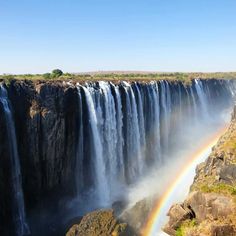 a large waterfall with a rainbow in the middle and water cascading over it