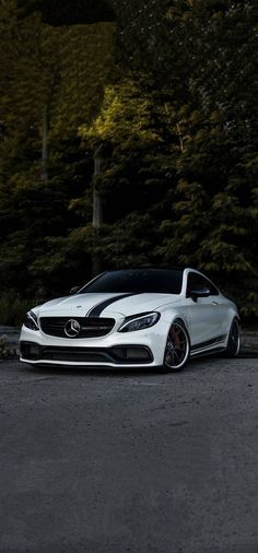 a white car parked in front of some trees