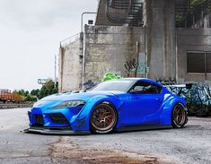 the blue sports car is parked in front of an old building with graffiti on it