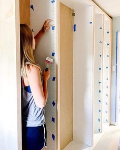 a woman is painting the walls in her room with blue adhesive tape on it