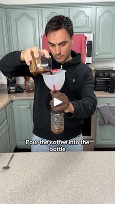 a man pouring something into a glass in the kitchen